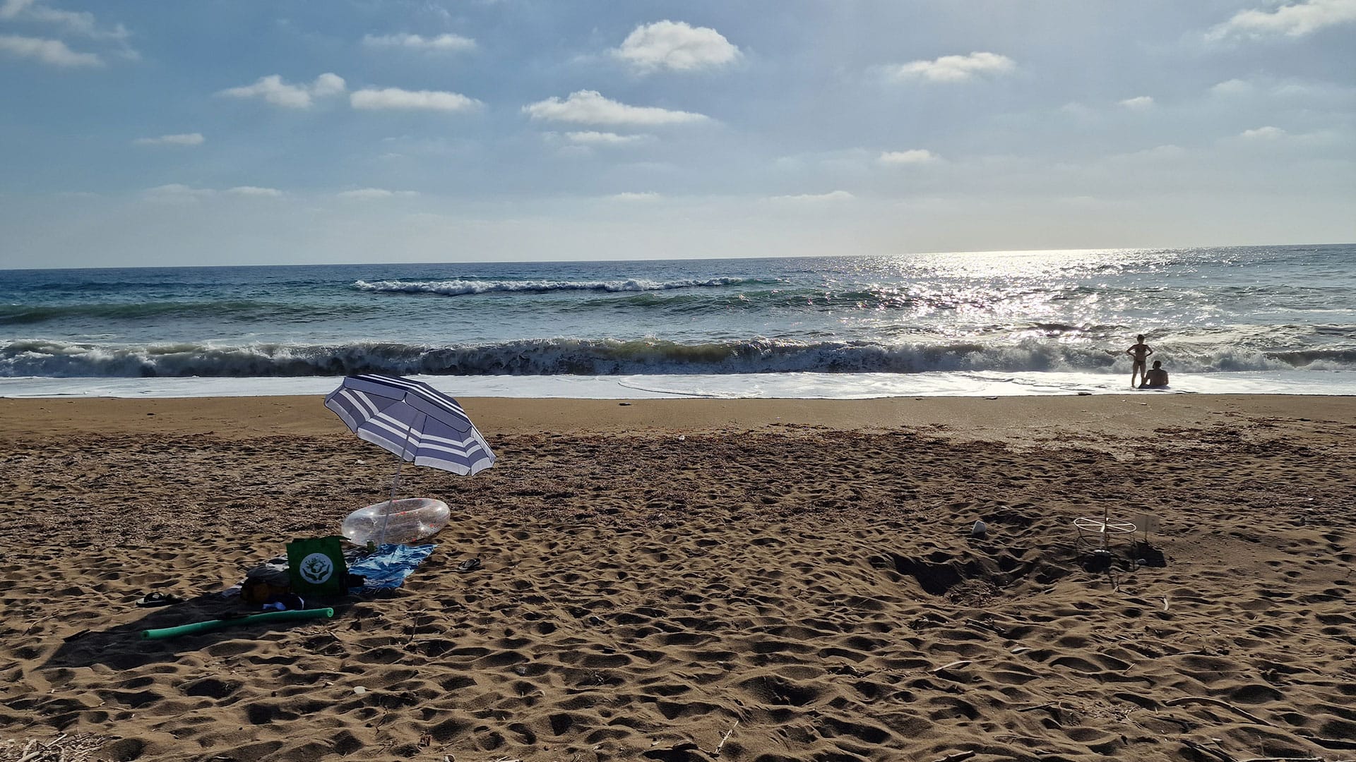 sun umbrella on the beach and a couple sunbathing close to the water